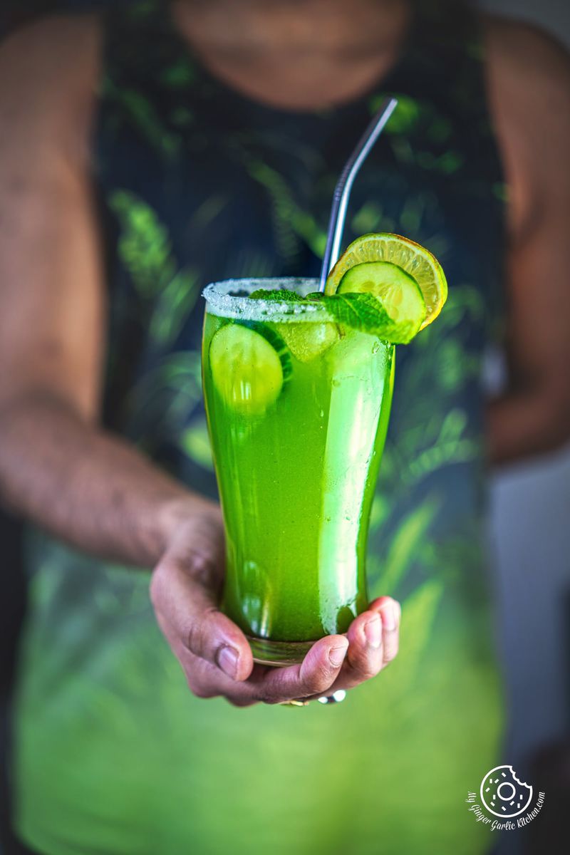 a man holding a cucumber mint cooler glass