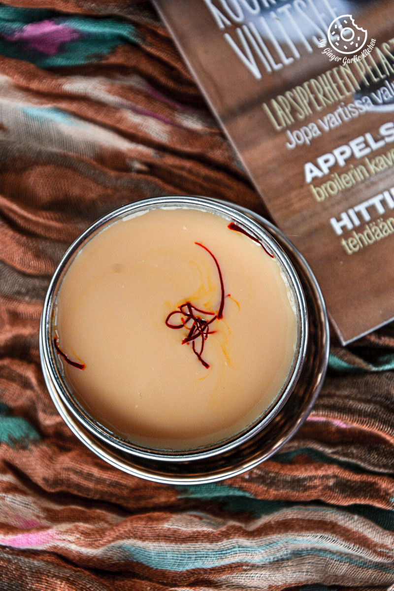 there is a small glass of spiced kesar chai with a saffron on it